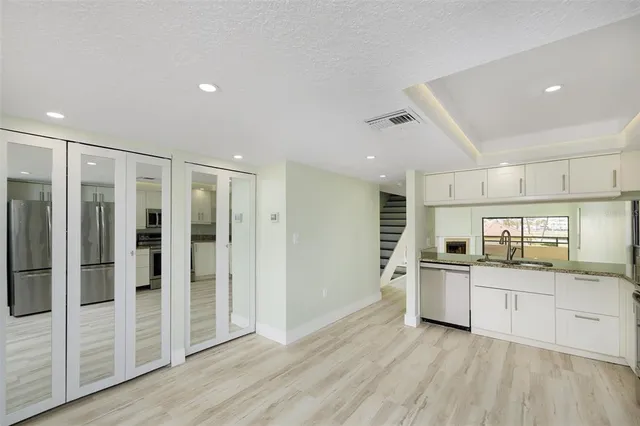 a large kitchen with a refrigerator and white cabinets