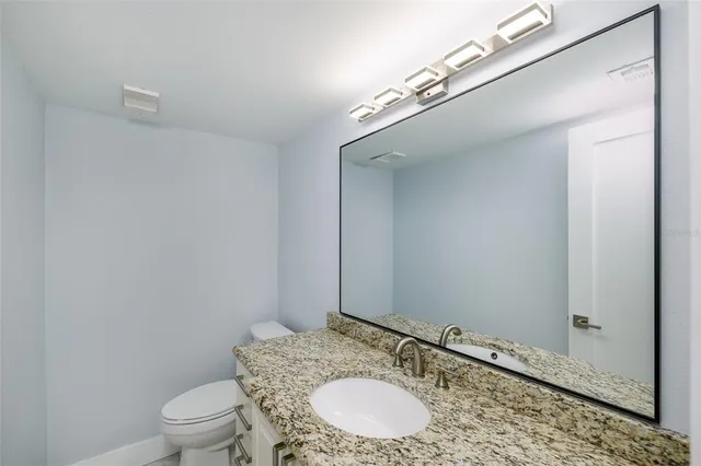 a bathroom with a granite countertop sink a toilet and a mirror