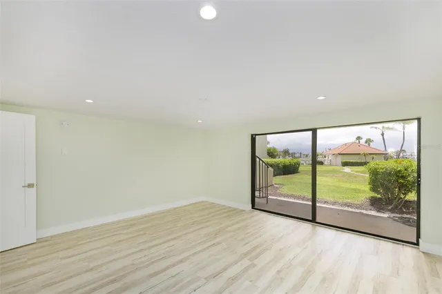an empty room with wooden floor and windows with curtains