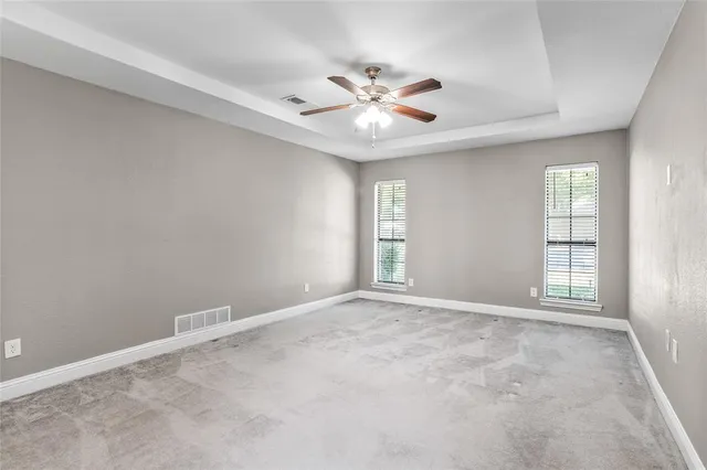 an empty room with windows and fan