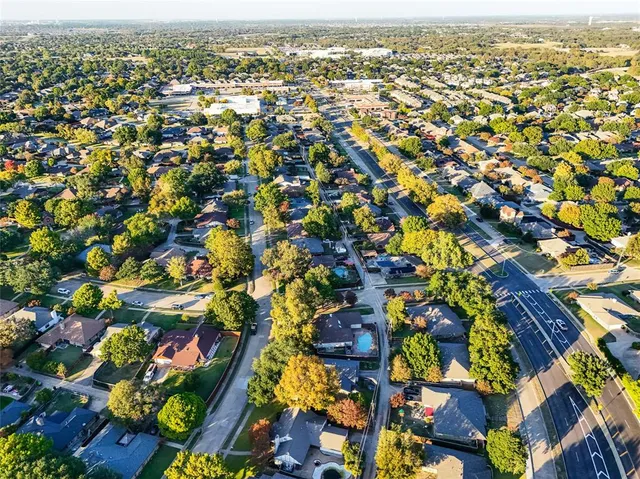 an aerial view of residential houses with outdoor space and trees