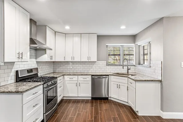 a kitchen with granite countertop sink stove and cabinets