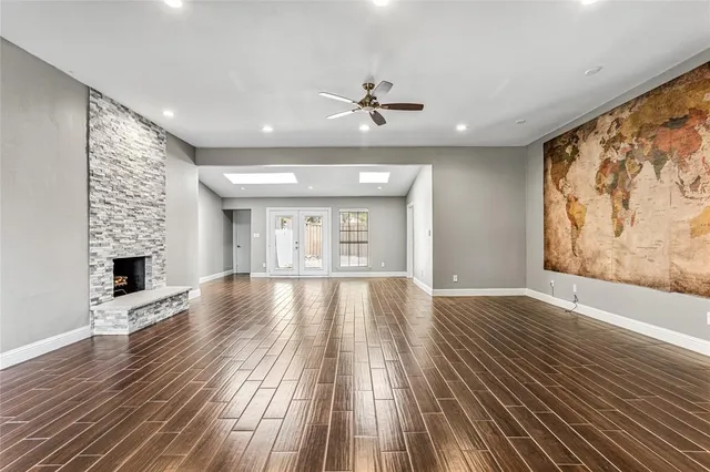 a view of an empty room with wooden floor and a fireplace