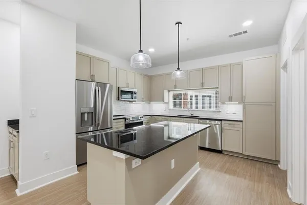 a kitchen with kitchen island a sink appliances a counter space and a window