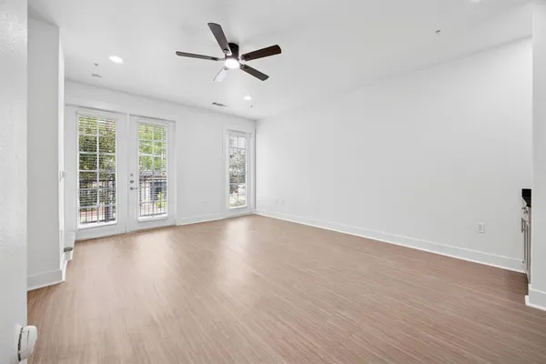 an empty room with wooden floor fan and windows