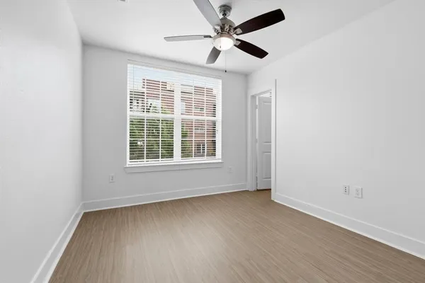 an empty room with wooden floor ceiling fan and windows