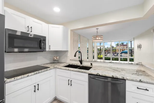 a kitchen with granite countertop a sink and a stove top oven with wooden floor