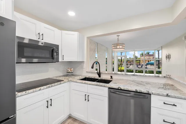a kitchen with granite countertop white cabinets and stainless steel appliances