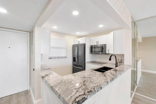 a kitchen with stainless steel appliances granite countertop a sink refrigerator and microwave