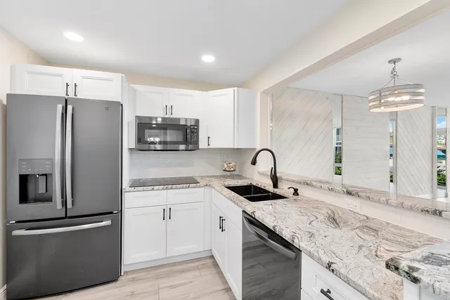a kitchen with granite countertop a refrigerator stove and sink