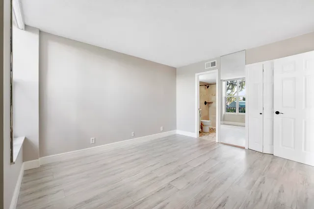a view of an empty room with wooden floor and closet