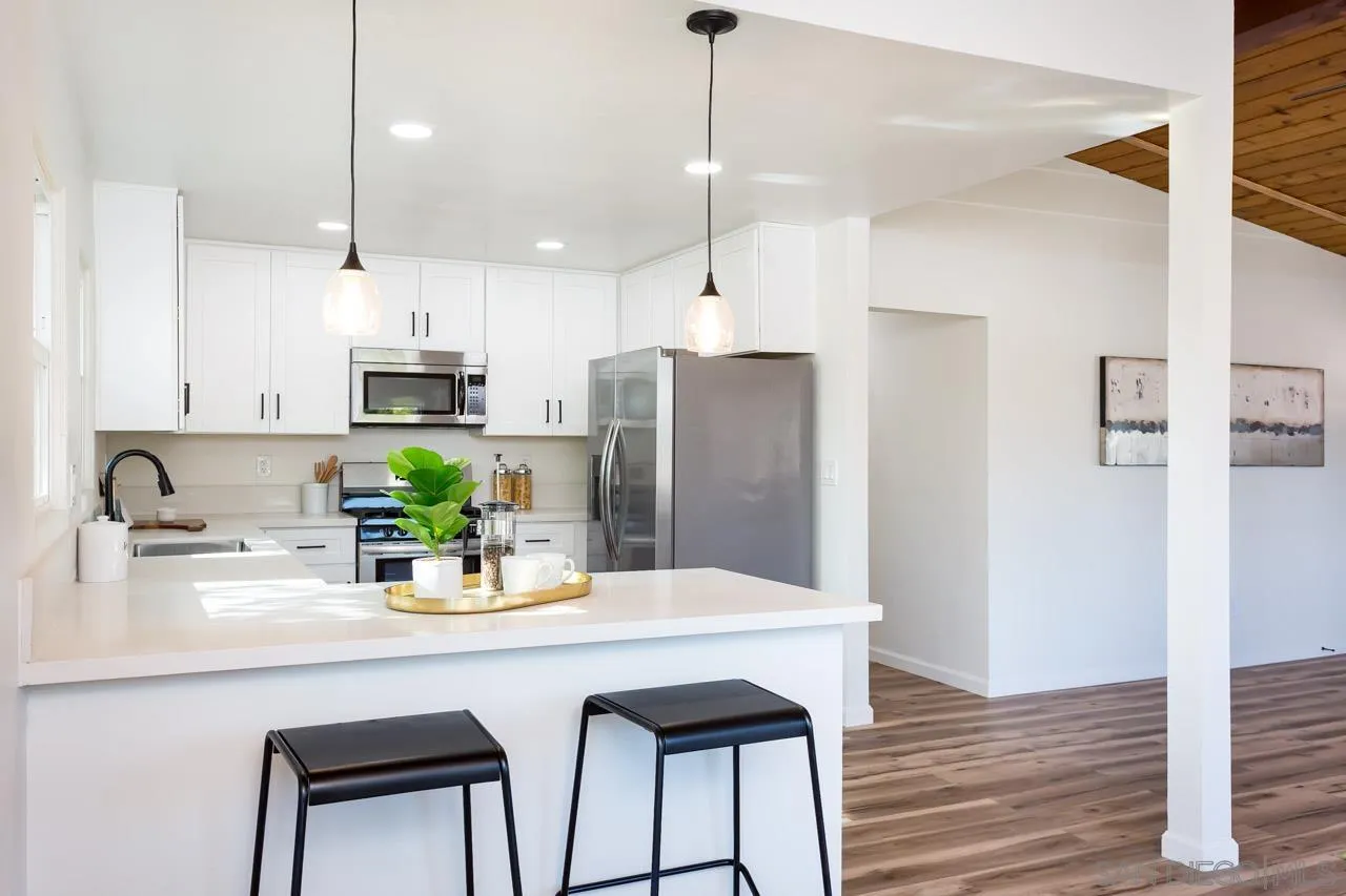 2610 Glebe Road Lemon Grove, CA 91945 - Photo 7 of 31 a kitchen with stainless steel appliances a dining table chairs refrigerator and sink