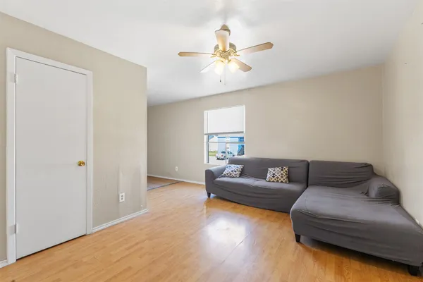 a living room with couches and a ceiling fan with wooden floor