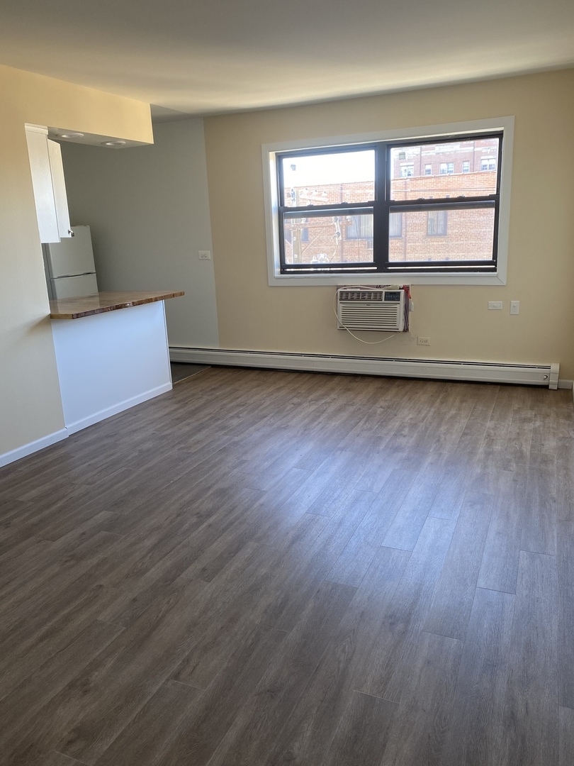 1025 West Hollywood Avenue, Unit 218 Chicago, IL 60660 - Photo 7 of 10 an empty room with wooden floor and windows
