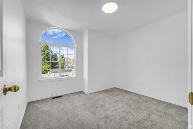 1147 West State Road Lehi, UT 84043 - Photo 21 of 31 Room featuring a large arched window with grid details, light gray carpeting, crisp white walls, and a recessed ceiling light fixture