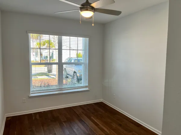 a view of an empty room with wooden floor and a window