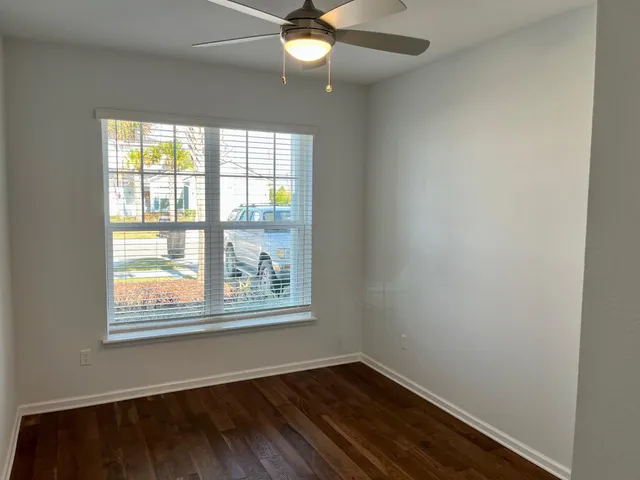 a view of an empty room with wooden floor and a window