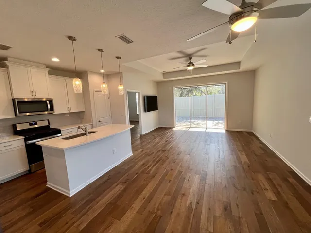 a large kitchen with kitchen island a stove a sink and a wooden floor