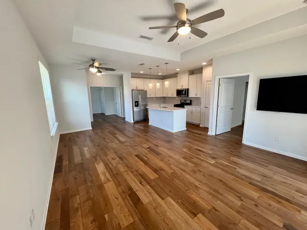 a view of a kitchen with wooden floor and a ceiling fan
