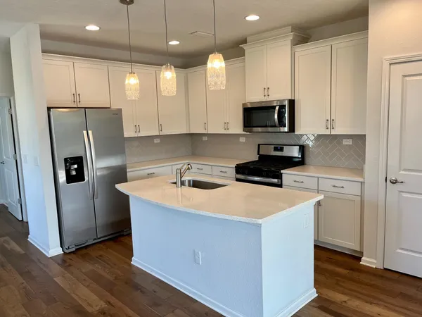 a kitchen with stainless steel appliances granite countertop a refrigerator a sink a stove and white cabinets