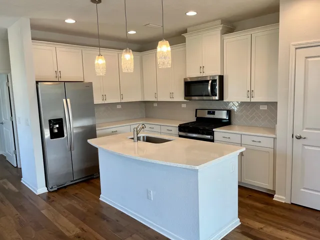 a kitchen with stainless steel appliances granite countertop a refrigerator a sink a stove and white cabinets