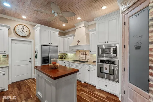 a kitchen with stainless steel appliances a refrigerator a stove a sink and a refrigerator with wooden floor