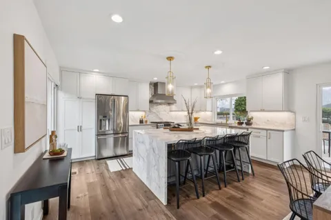 a kitchen with stainless steel appliances a table chairs stove and refrigerator