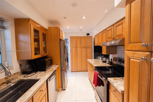 a kitchen with granite countertop a sink stove and refrigerator