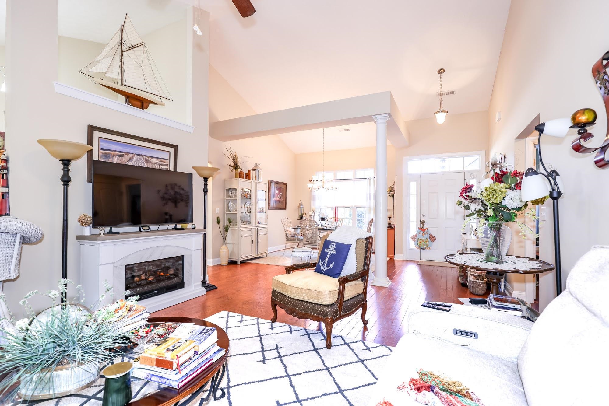 147 Quail Hollow Road Myrtle Beach, SC 29579 - Photo 3 of 35 Living room with hardwood / wood-style floors, high vaulted ceiling, decorative columns, a chandelier, and a glass covered fireplace