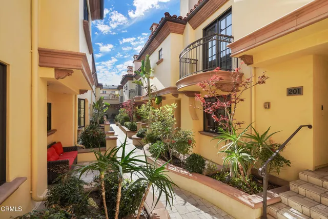a view of a white house with potted plants