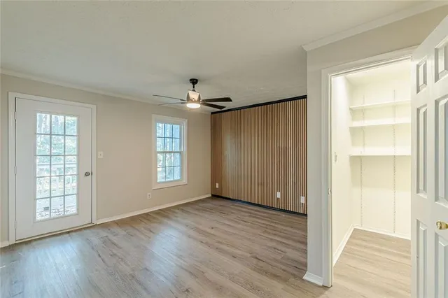 a view of an empty room with wooden floor and a window