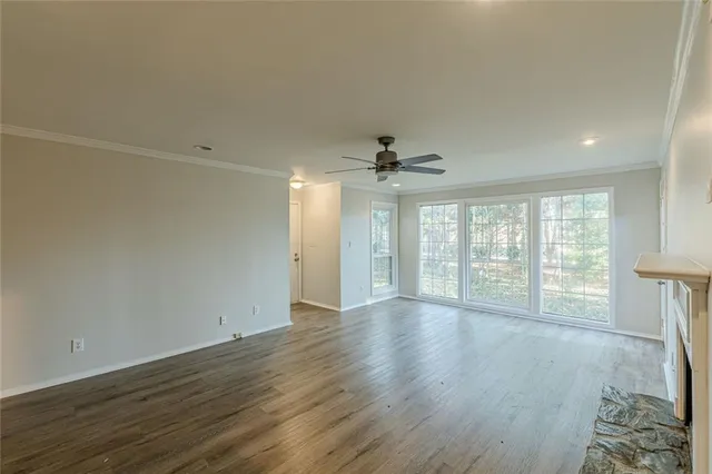 an empty room with wooden floor fan and windows