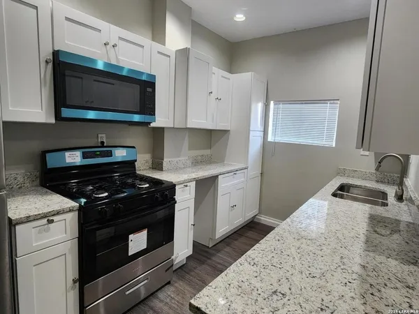 a kitchen with stainless steel appliances a stove a microwave a sink and cabinets