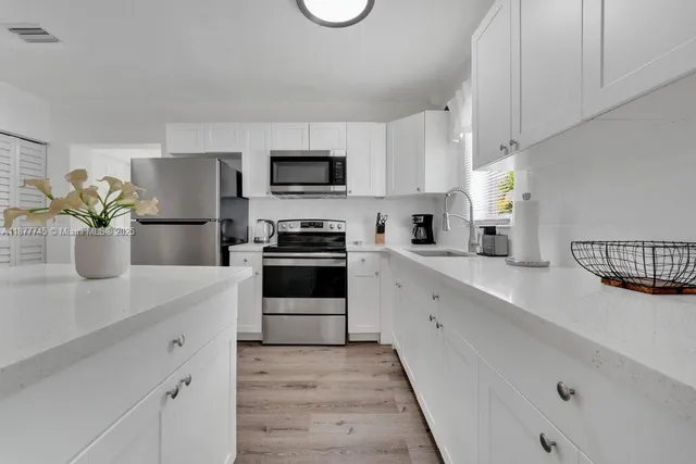 a kitchen with a sink stainless steel appliances and white cabinets