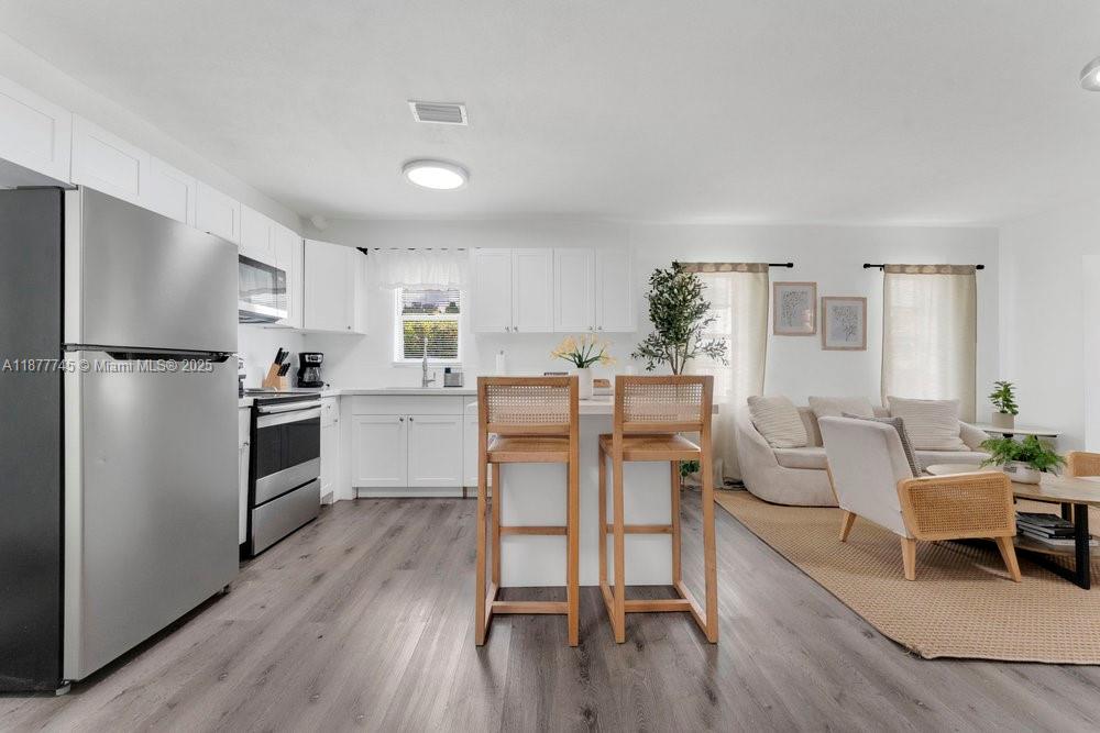 180 Northwest 69th Street Miami, FL 33150 - Photo 12 of 31 a kitchen with a table chairs refrigerator and microwave