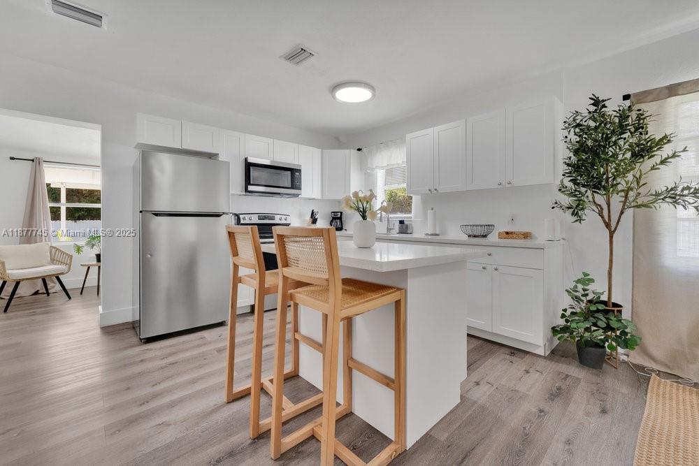 180 Northwest 69th Street Miami, FL 33150 - Photo 10 of 31 a kitchen with a table chairs refrigerator and microwave