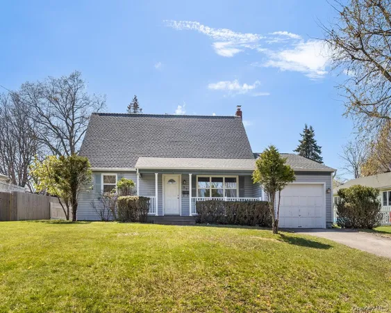 a front view of house with yard and trees in the background