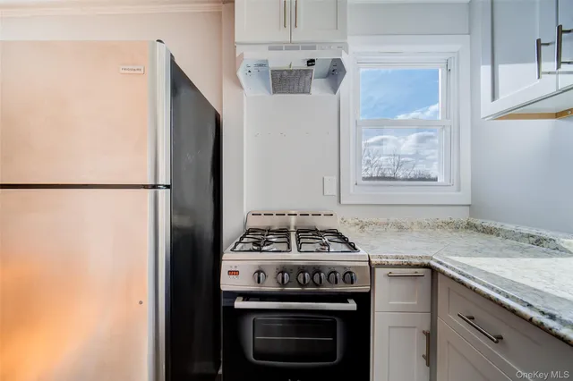 a kitchen with granite countertop a sink stove and refrigerator