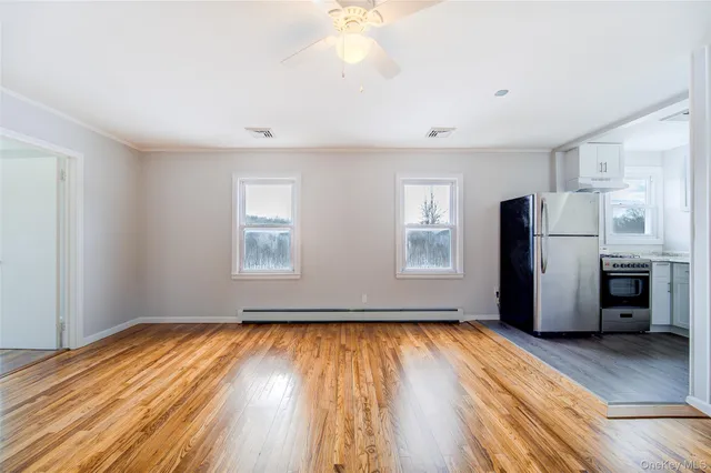 a view of empty room with wooden floor and window