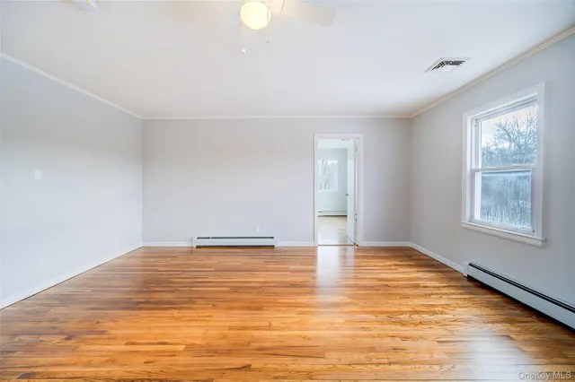 a view of an empty room with window and wooden floor