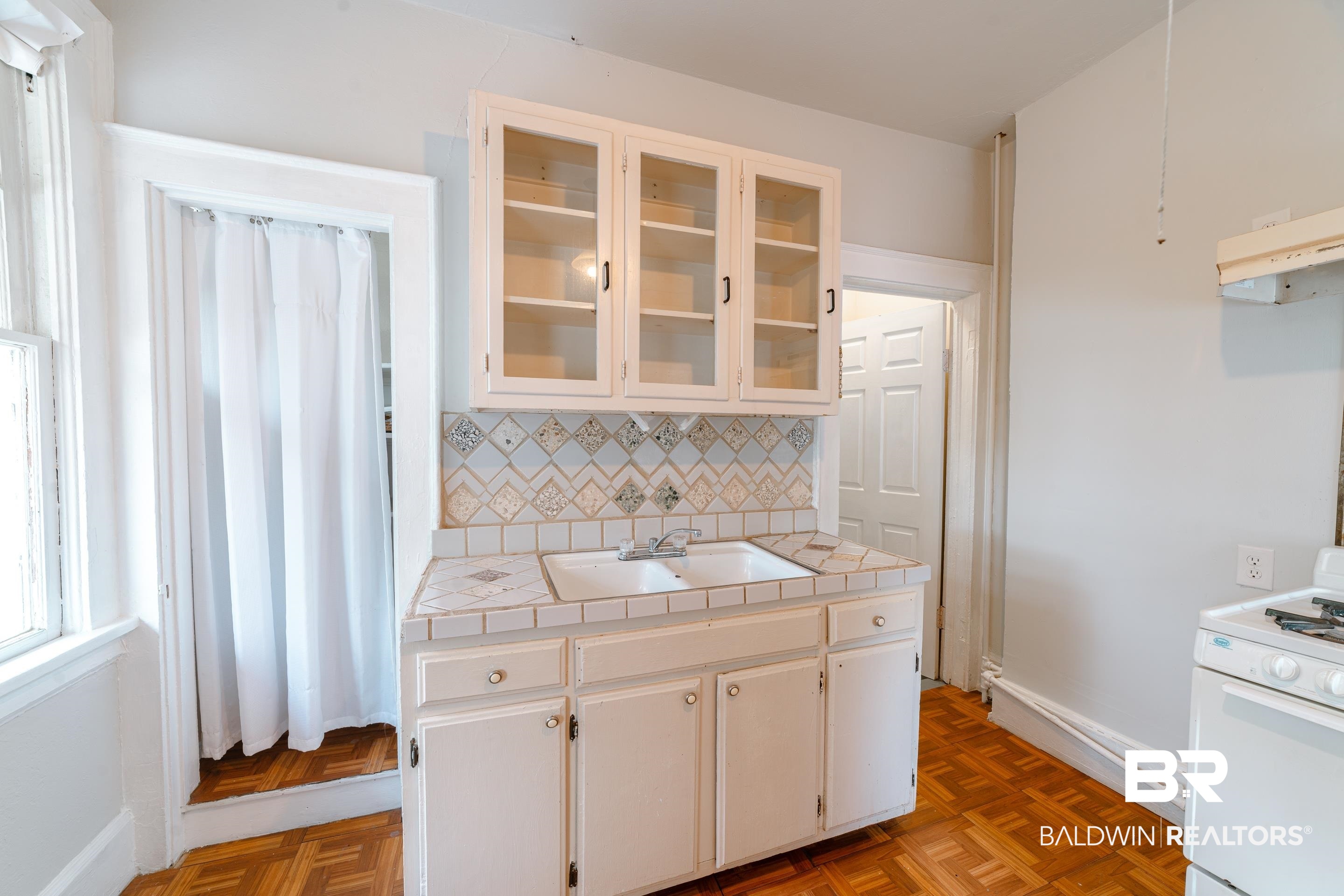 312 1st Street Mobile, AL 36611 - Photo 10 of 29 Kitchen with tile counters, backsplash, white range oven, sink, and white cabinets