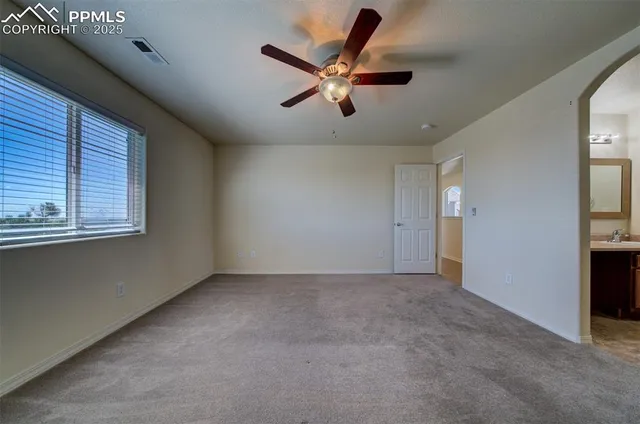 an empty room with ceiling fan and windows