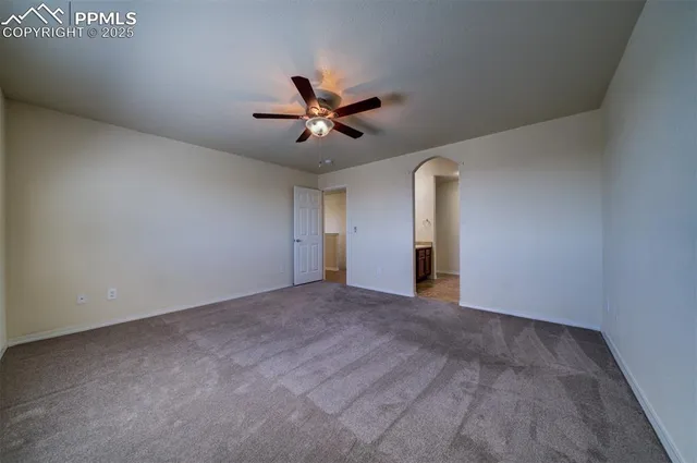 a view of an empty room with a ceiling fan and window