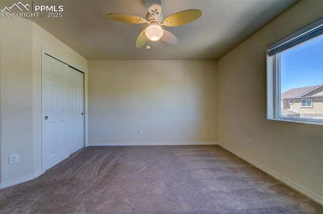 an empty room with a chandelier fan and windows