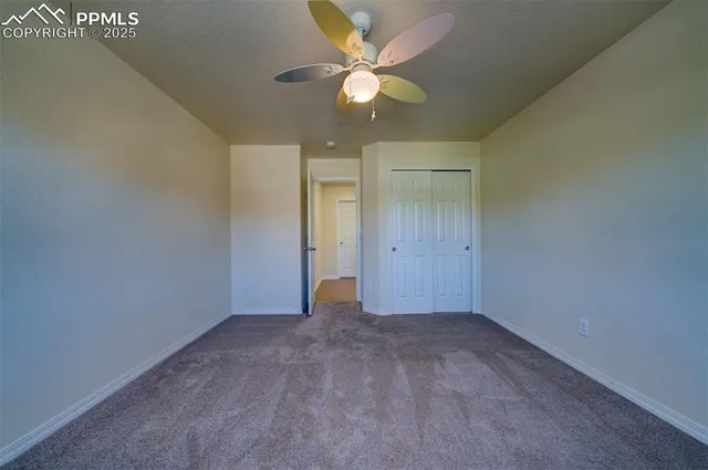 an empty room with closet and a chandelier fan