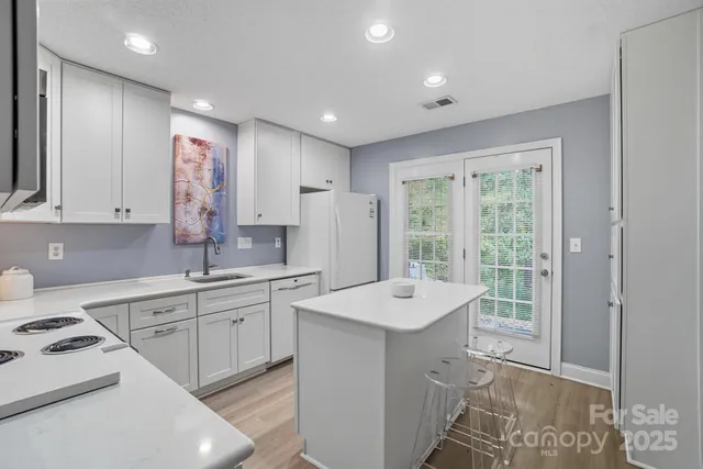 a large white kitchen with a sink a stove a refrigerator and cabinets