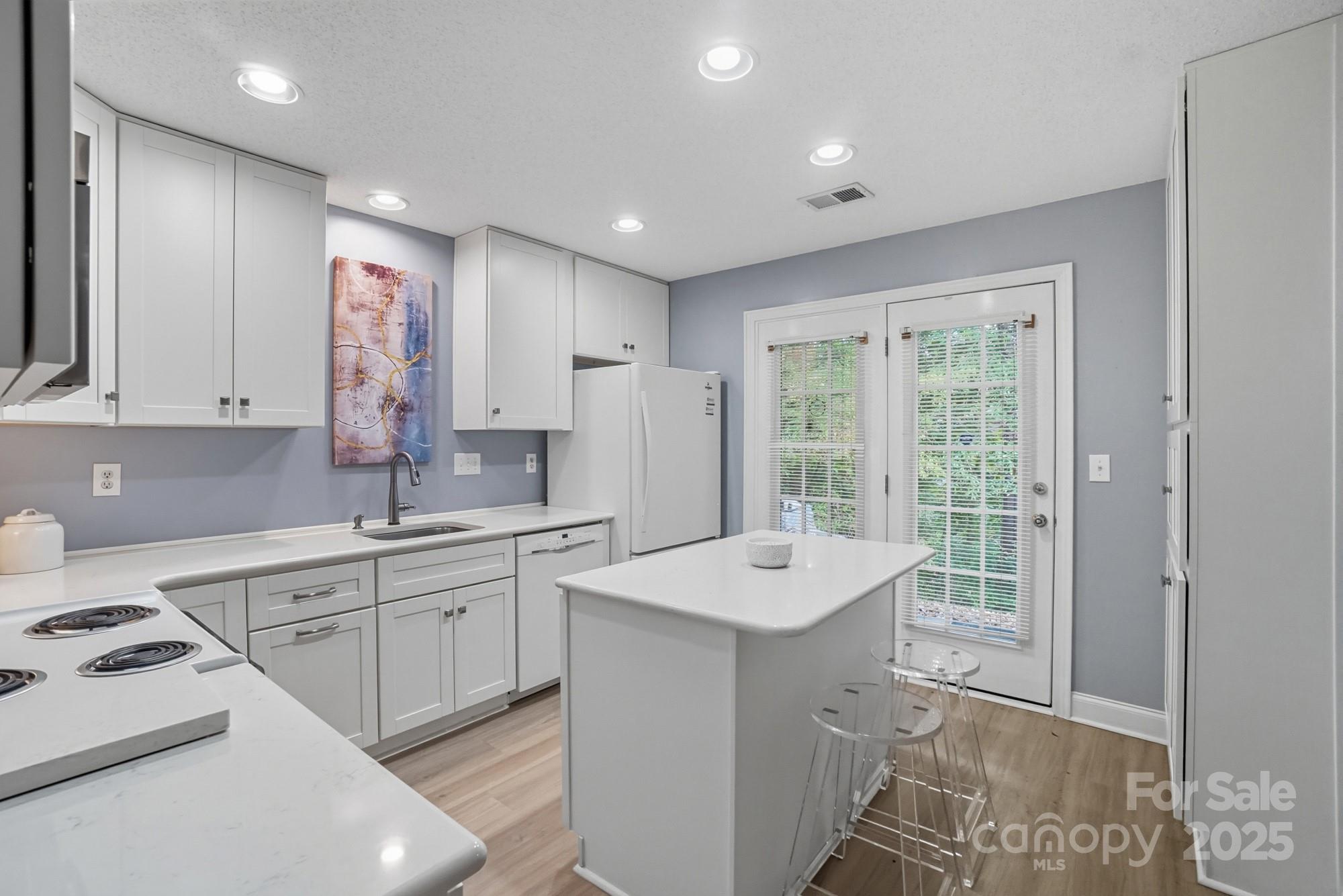 9166 Exbury Court Charlotte, NC 28269 - Photo 12 of 31 a large white kitchen with a sink a stove a refrigerator and cabinets