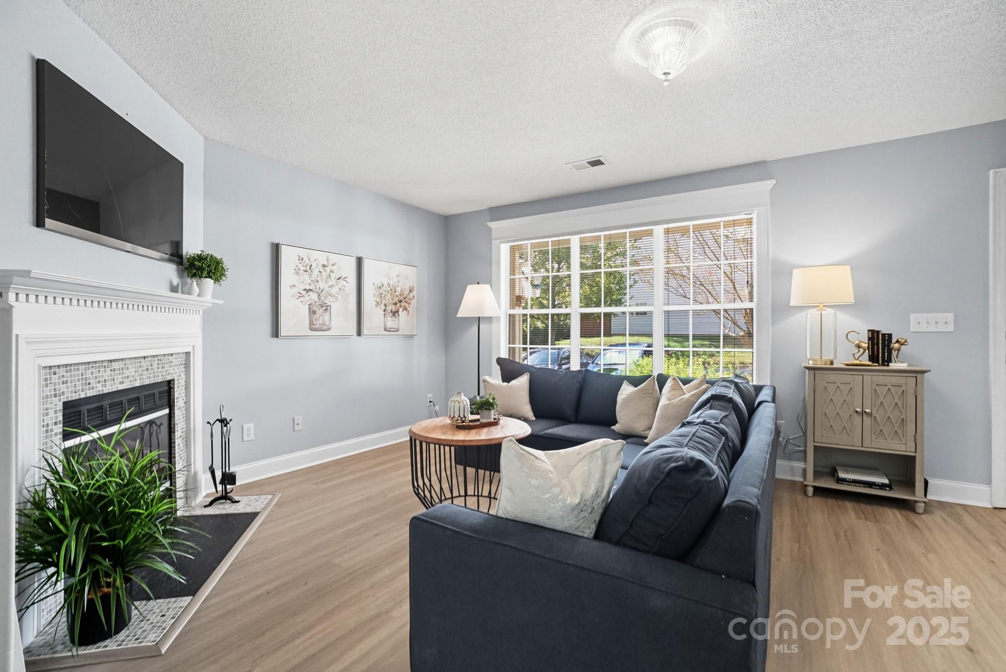 9166 Exbury Court Charlotte, NC 28269 - Photo 7 of 31 a living room with furniture a flat screen tv and a fireplace