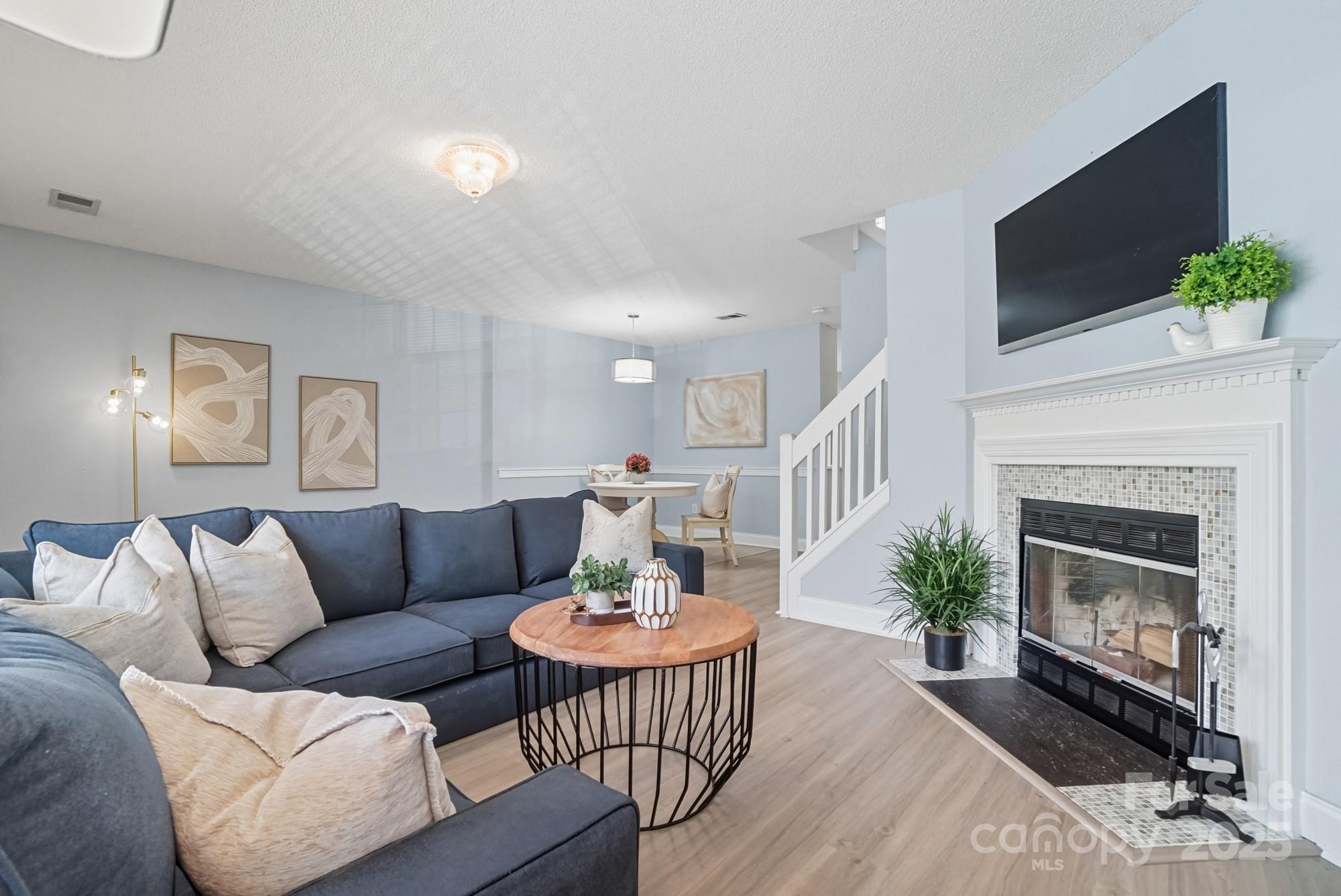 9166 Exbury Court Charlotte, NC 28269 - Photo 8 of 31 a living room with furniture a fireplace and a flat screen tv