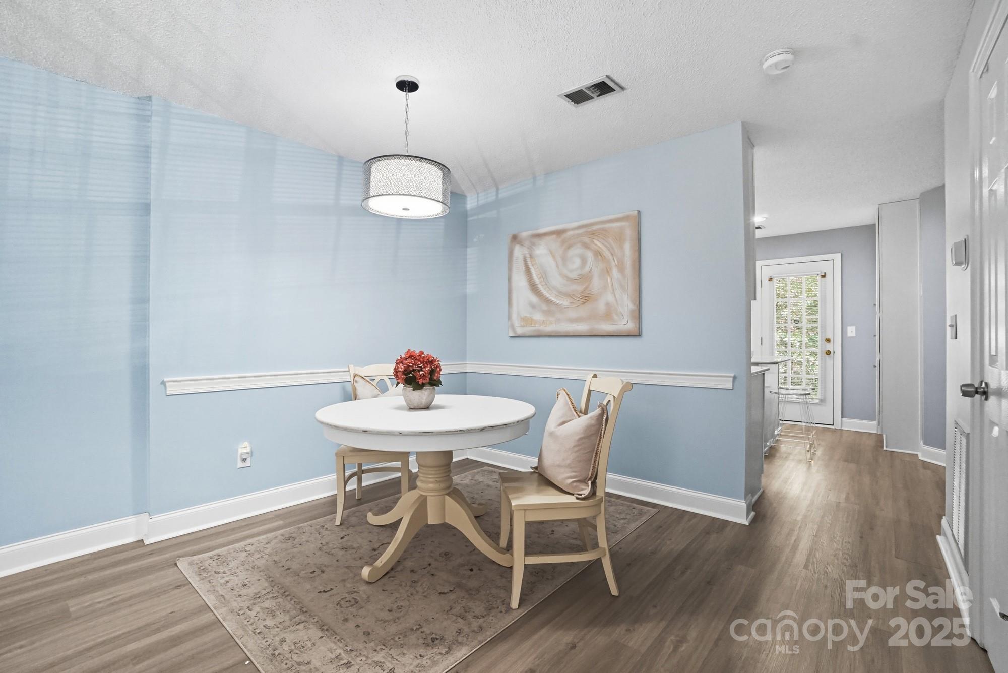 9166 Exbury Court Charlotte, NC 28269 - Photo 10 of 31 a dining room with wooden floor a chandelier a wooden table and chairs